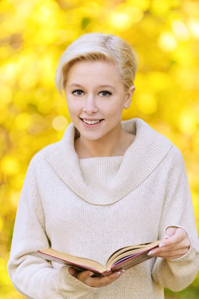 Portrait of smiling blond woman with book — Stock Photo, Image
