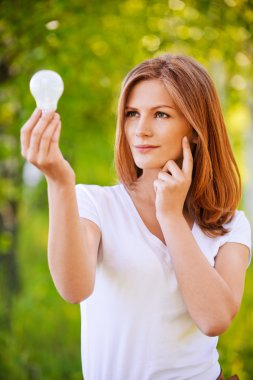 Portrait of young woman looking at electric bulb clipart