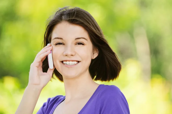 Портрет молодой улыбающейся женщины, говорящей по телефону — стоковое фото