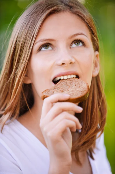 Porträt einer schönen jungen Frau beim Brotessen — Stockfoto