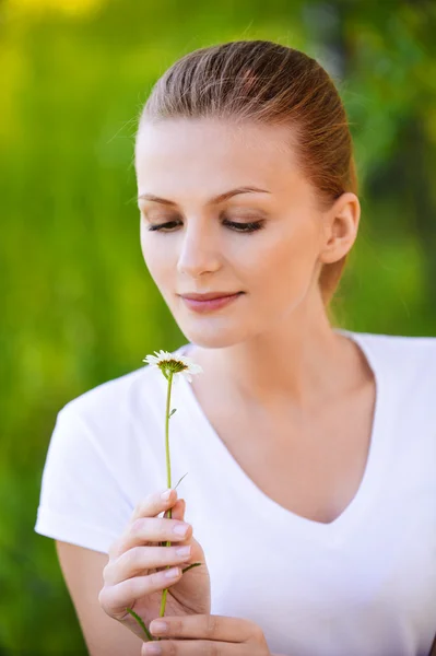 Retrato de jovem bela mulher olhando para flor de camomila — Fotografia de Stock