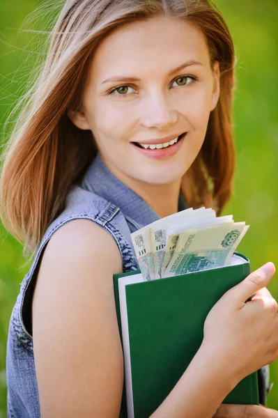 Портрет усміхненої жінки, що тримає книгу з грошима — стокове фото