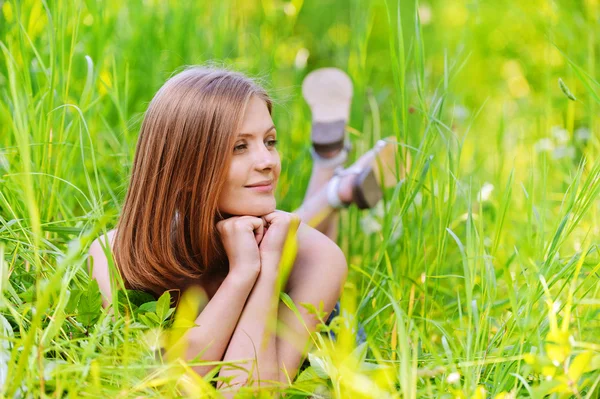 Jonge vrouw liggen in gras — Stockfoto