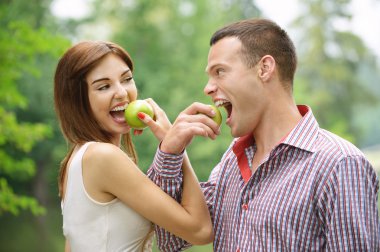 Two young happy eating apples