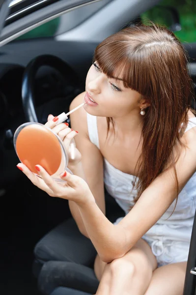 Portrait of young woman making herself up in car — Stock Photo, Image