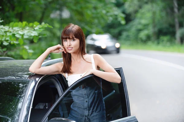 Arabanın yanında çekici genç esmer kadın — Stok fotoğraf