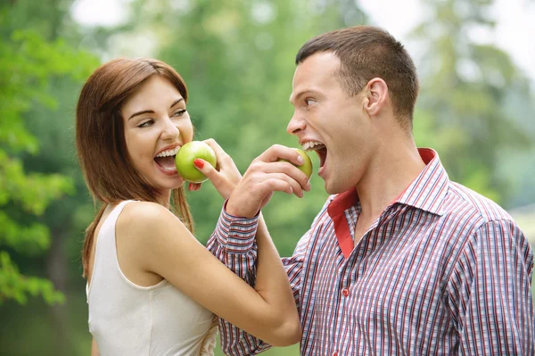 Dois jovens felizes comendo maçãs — Fotografia de Stock