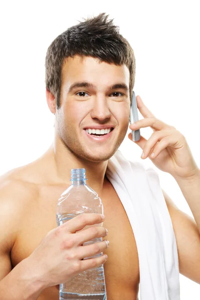 Portrait of young man holding bottle and speking on telephone — Stock Photo, Image
