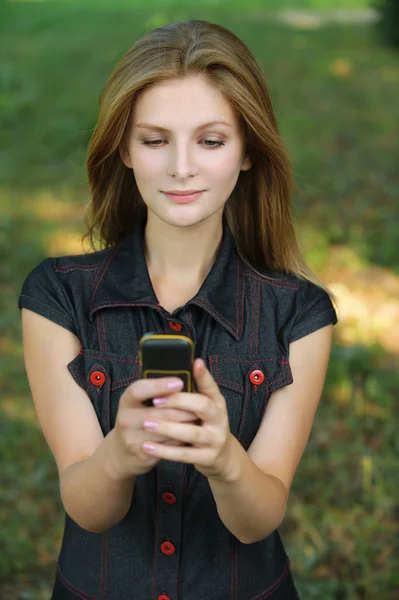 Portrait of young fair-haired woman looking at mobile phone — Stock Photo, Image