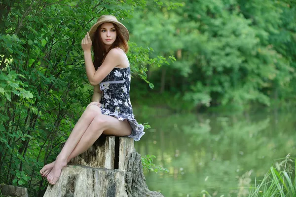 Portrait of young woman sitting on stump — Stock Photo, Image