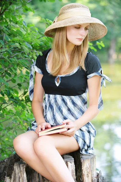 Portrait of woman holding book and sitting on stump — Stock Photo, Image
