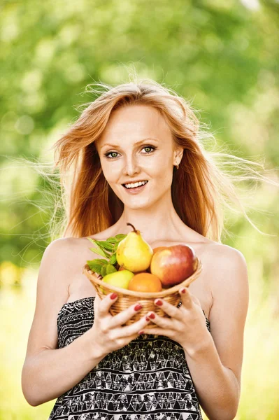 Portrait of young pretty fair-haired woman holding basket full o — Stock Photo, Image