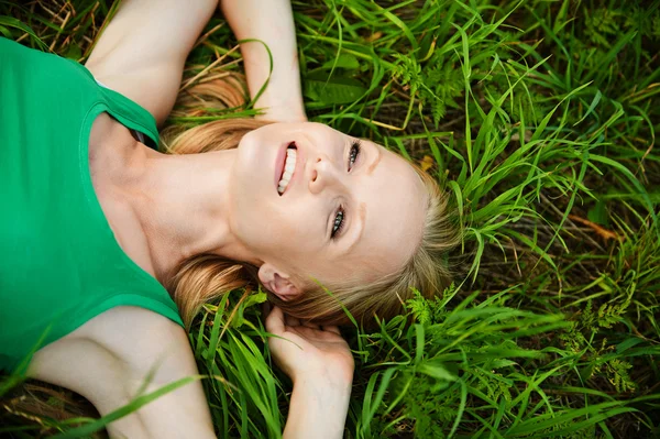 Portret van jonge mooie vrouw liggen op gras — Stockfoto