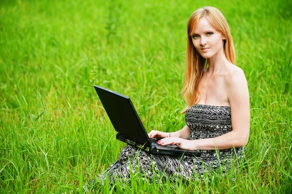 Portret van jonge blonde vrouw die werkt met laptop Stockfoto