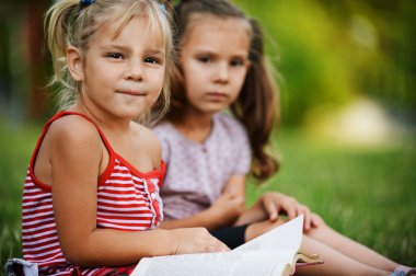 Two little pretty girls reading book clipart