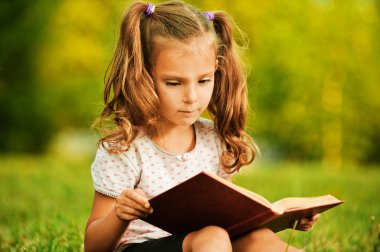 Portrait of little cute girl reading book clipart