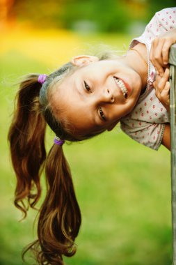 Portrait of little pretty girl playing at summer green park clipart