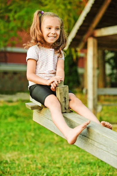 Маленькая улыбающаяся девочка на качелях — стоковое фото