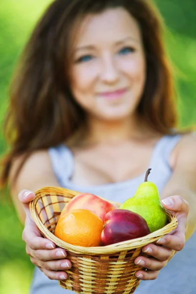 Jolie femme tenant panier plein de fruits — Photo