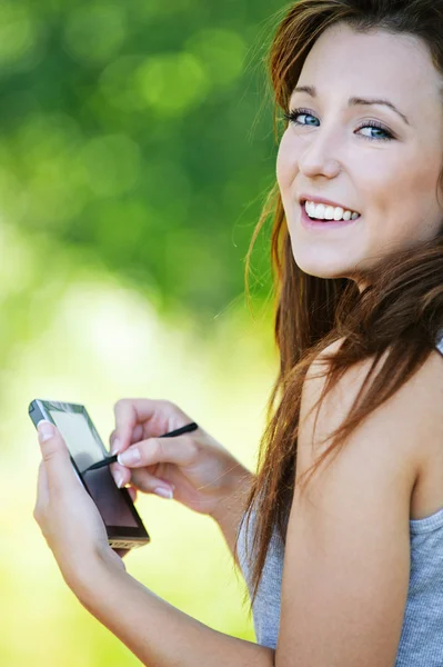 Young smiling brunette woman holding smartphone and stylus — Stock Photo, Image