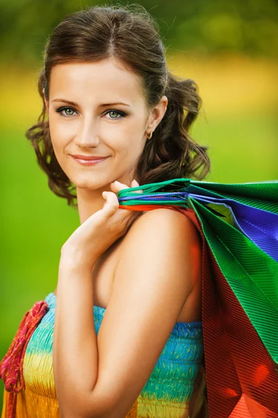 Retrato de jovem mulher sorridente segurando muitos sacos — Fotografia de Stock
