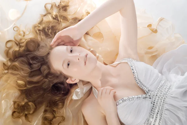 Portrét krásné mladé ženy s prstýnky vlasů ležící — Stock fotografie