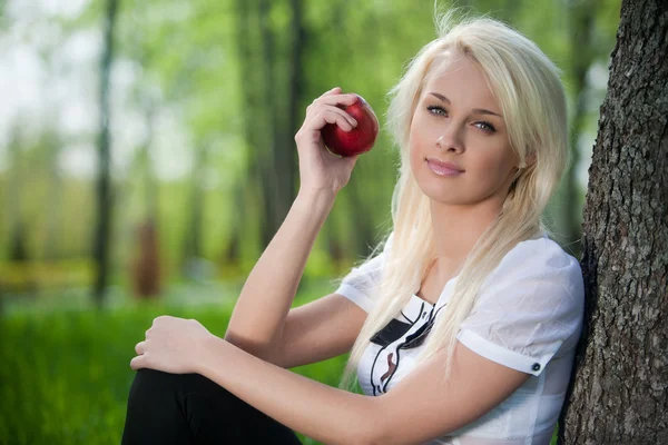 Young woman sits near tree in park — Stock Photo, Image