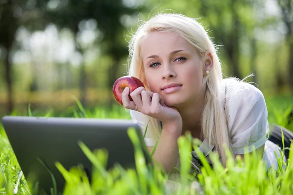 Mooie jonge vrouw met laptop in park — Stockfoto