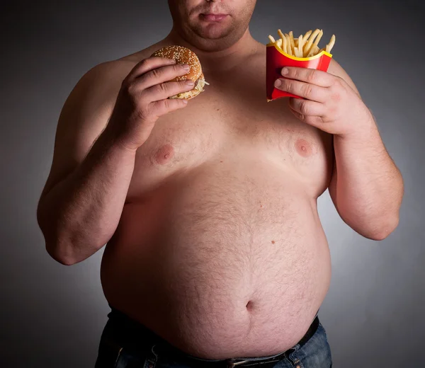 Dicker Mann mit Hamburger und Pommes — Stockfoto