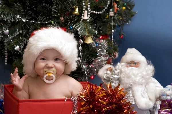 Χαριτωμένο μωρό σε κόκκινο καπέλο μπροστά από το χριστουγεννιάτικο δέντρο Royalty Free Φωτογραφίες Αρχείου