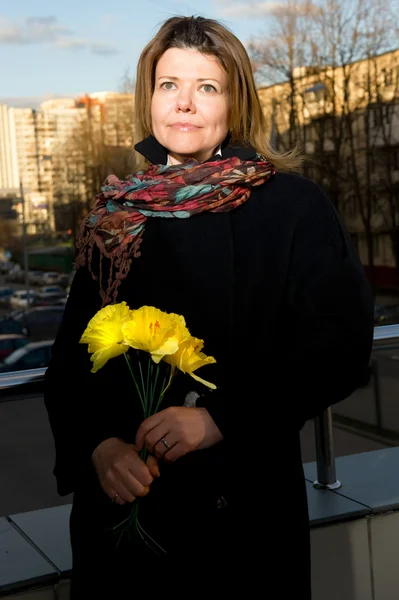 Жінка на вулиці з жовтими квітами — стокове фото