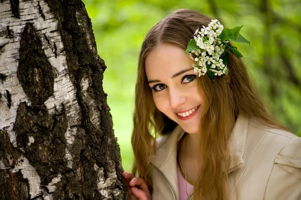 Ung flicka med blommor i håret på nära håll — Stockfoto