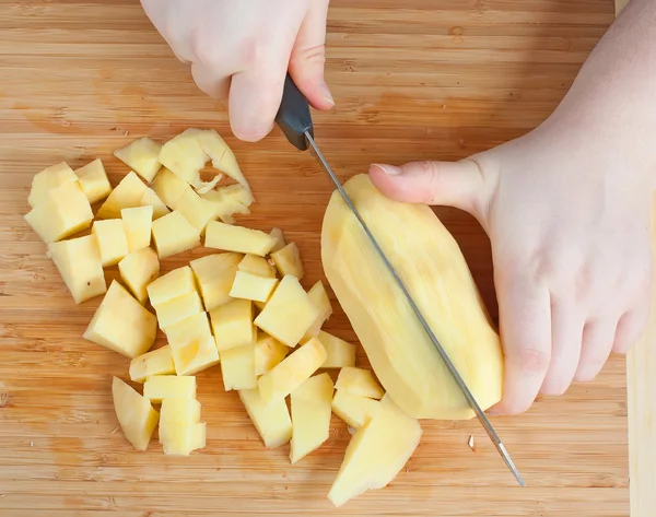Las manos femeninas cortar patatas — Foto de Stock