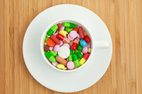 Cup with multicolored tablets and capsules — Stock Photo, Image
