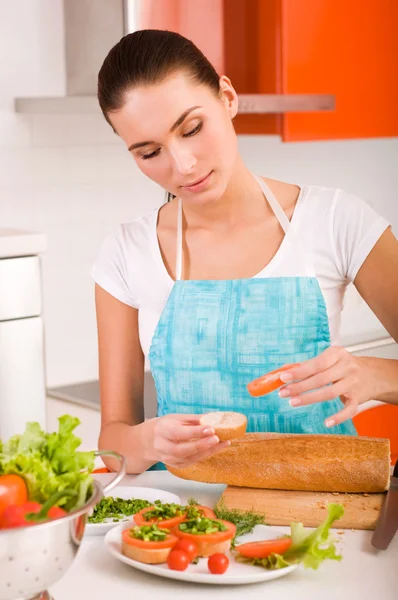 Mulher sorridente atraente preparando sanduíches saudáveis frescos em h — Fotografia de Stock