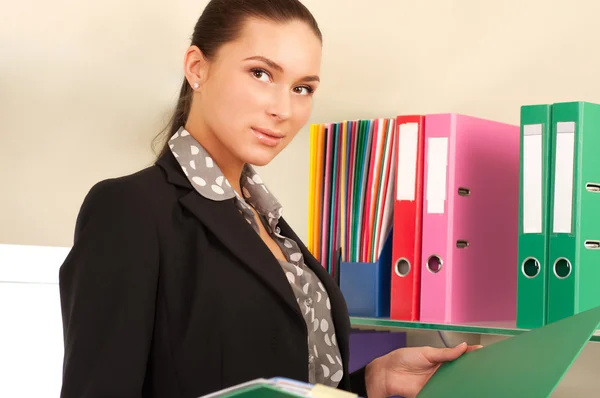 Business woman in front of shelves with folders — Stock Photo, Image