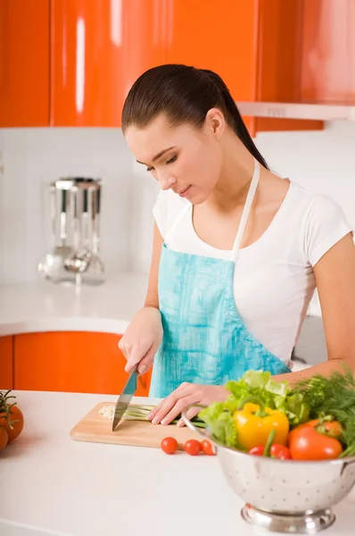 Mujer joven cortando verduras en una cocina —  Fotos de Stock