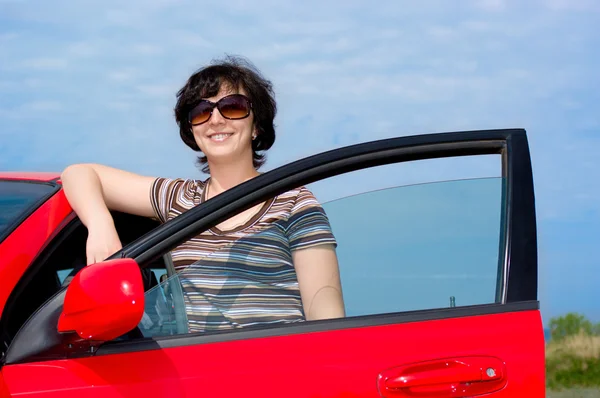 Молодая женщина с красной машиной — стоковое фото
