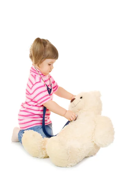 stock image Little girl listens a stethoscope to a toy bear