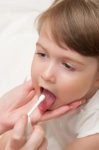 Doutor espirrando aerossol uma garganta à menina — Fotografia de Stock