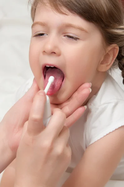 Doutor espirrando aerossol uma garganta para menina — Fotografia de Stock