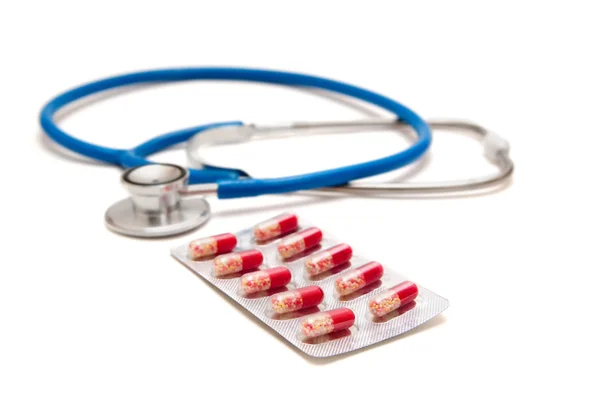 Синий стетоскоп с красными таблетками — стоковое фото
