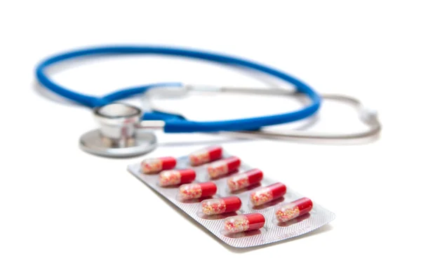 Синий стетоскоп с красными таблетками — стоковое фото