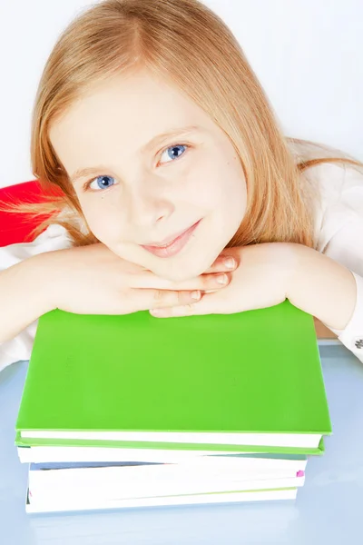 Улыбающаяся маленькая девочка с книгами на столе — стоковое фото