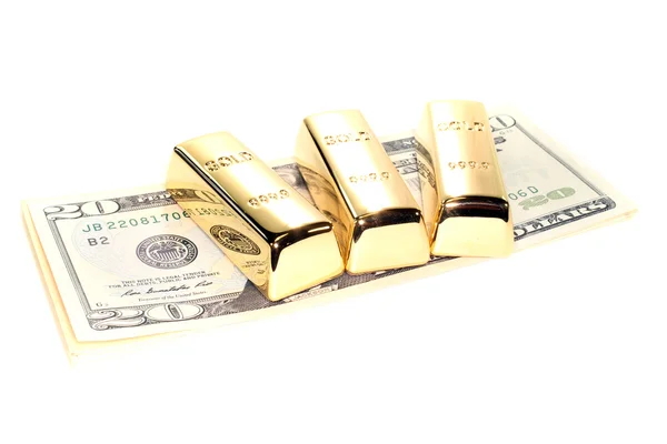 Три золотых слитка на долларах — стоковое фото