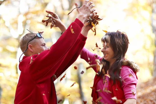 Young couple enjoying the falling leaves