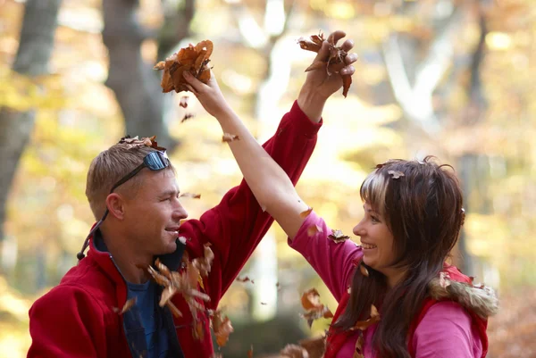 Young couple enjoying the falling leaves — Stock Photo, Image