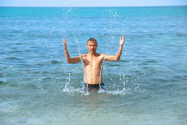 Hombre feliz en el mar con salpicaduras — Foto de Stock