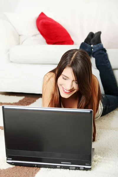 Jonge vrouwelijke liggend op de vloer met behulp van laptop. — Stockfoto