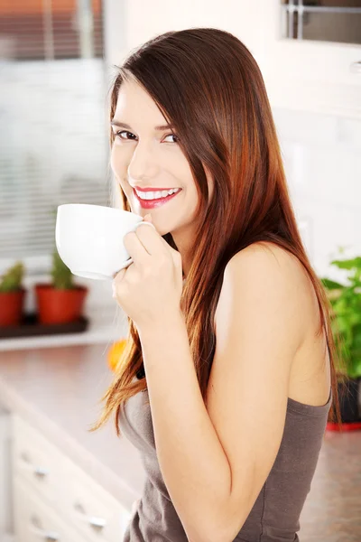 Beautiful woman in the kitchen drinking something — Stock Photo, Image